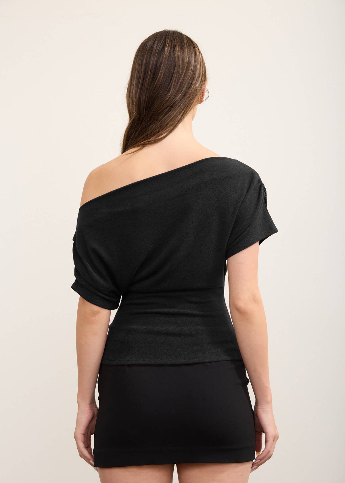 backside of women wearing black one shoulder knit top with mini skirt