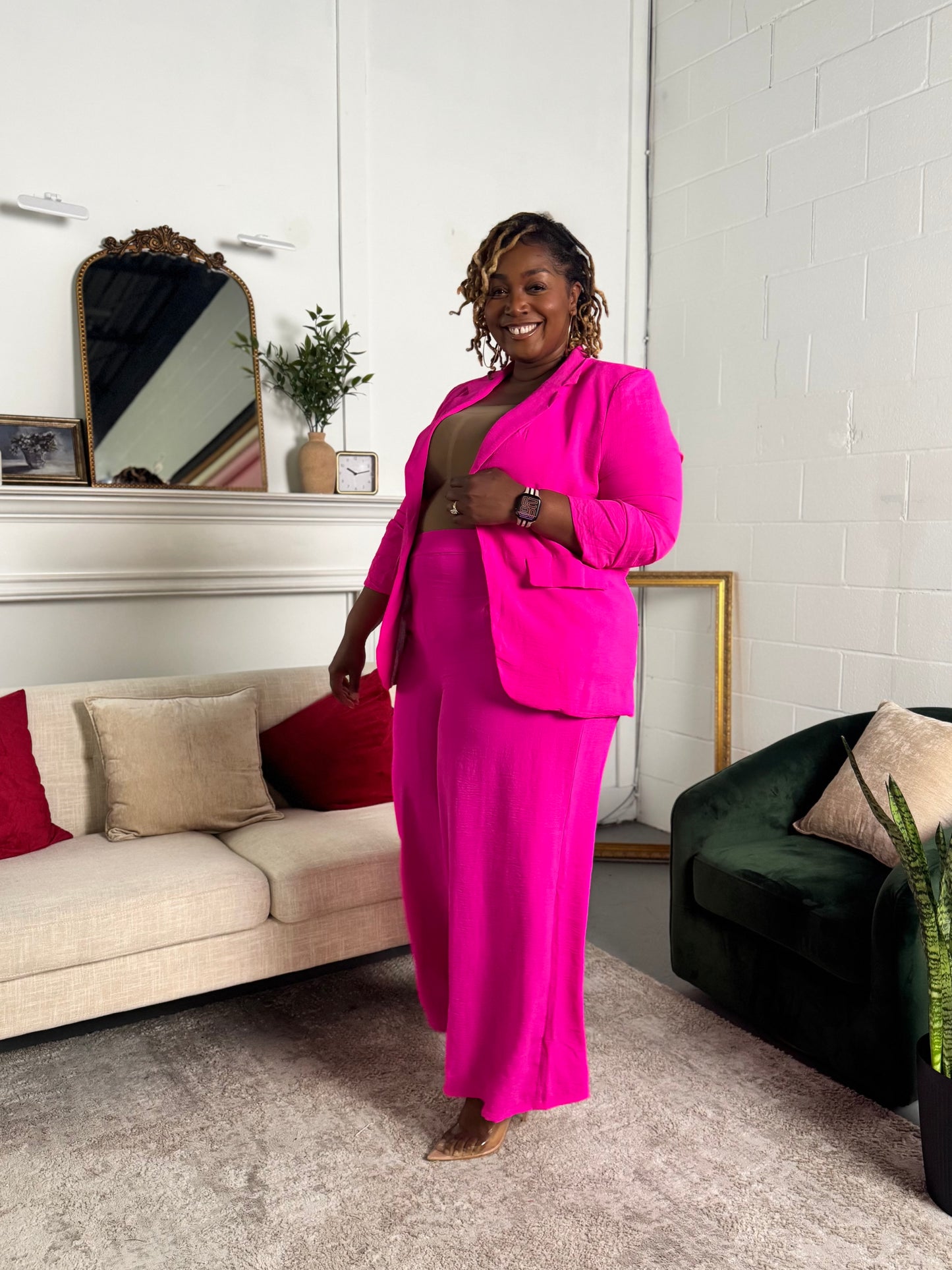 Woman in a bright pink suit standing in a living room.