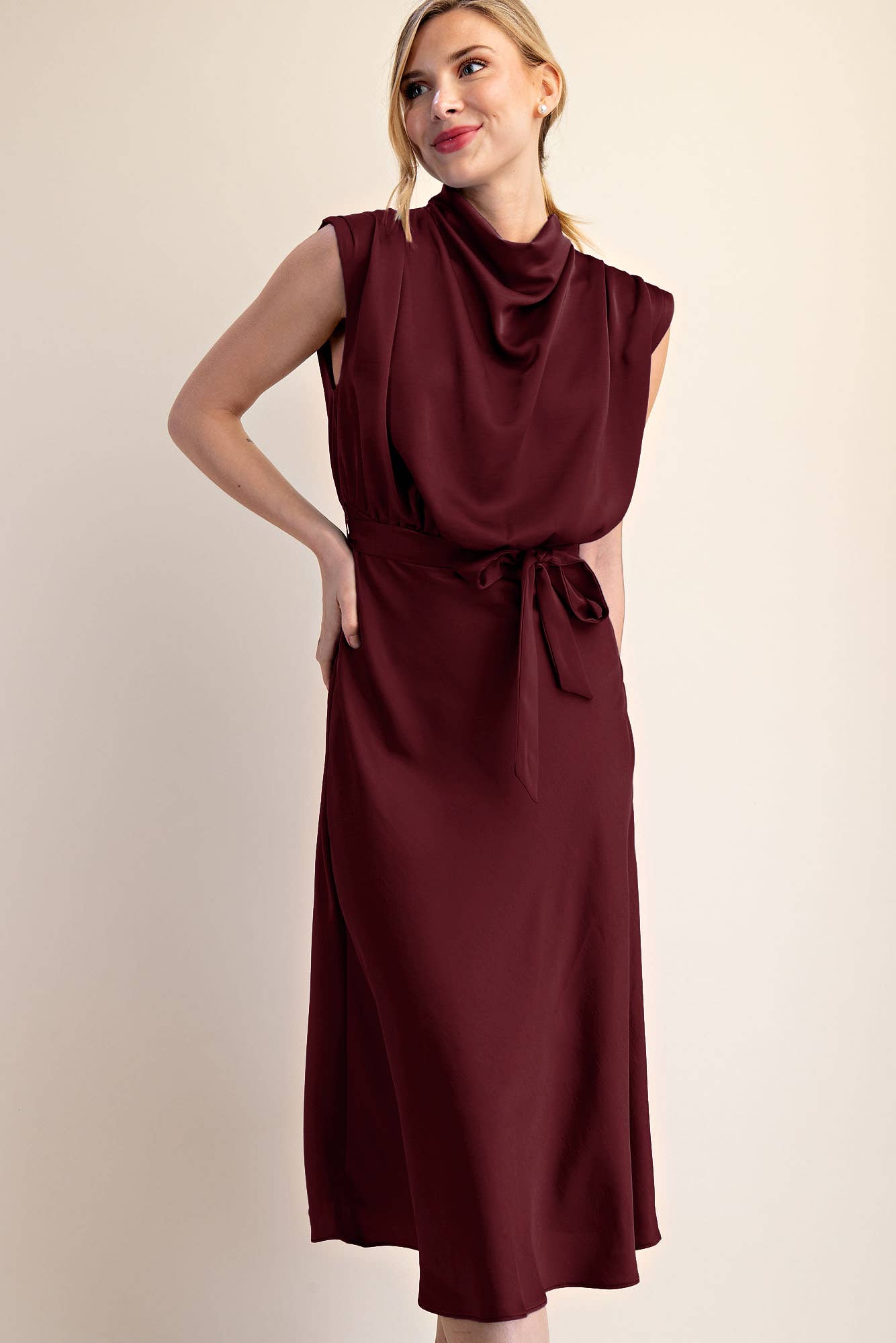 Woman wearing a burgundy dress against a beige background