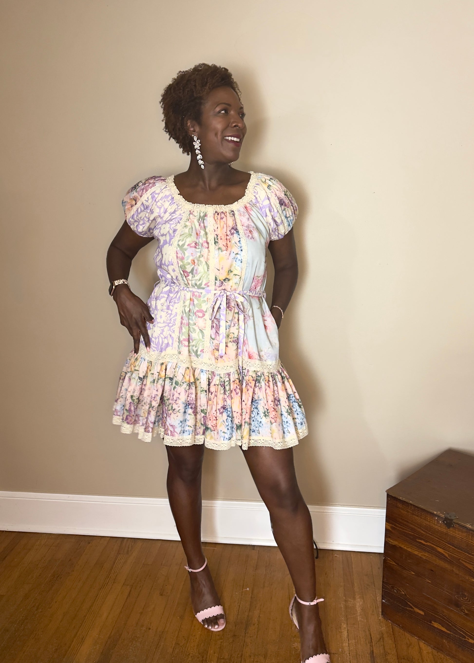 Woman wearing a short mixed floral dress standing against a beige wall.