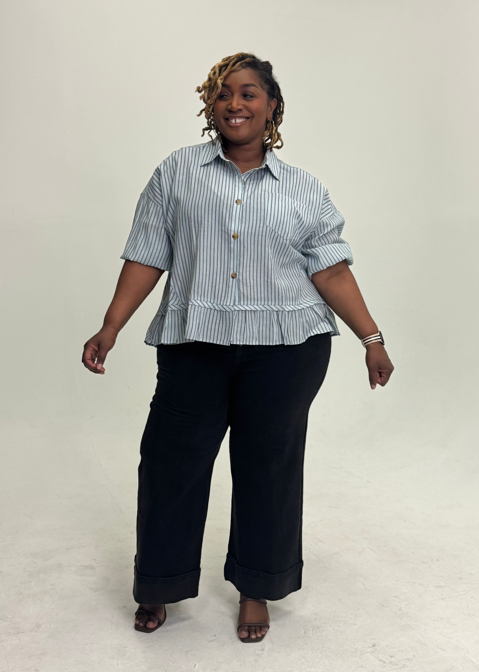 Woman wearing a striped shirt and black pants on a plain background