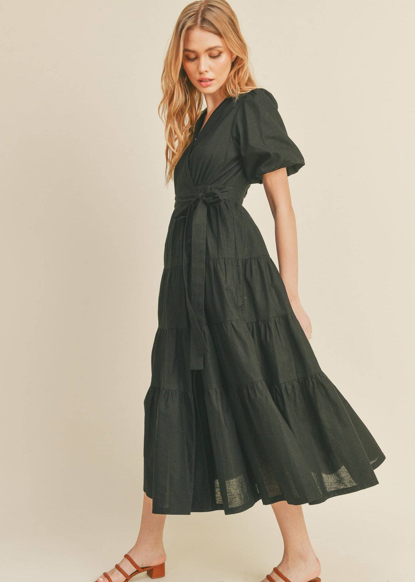 side view of women wearing black bubble sleeve midi wrap dress