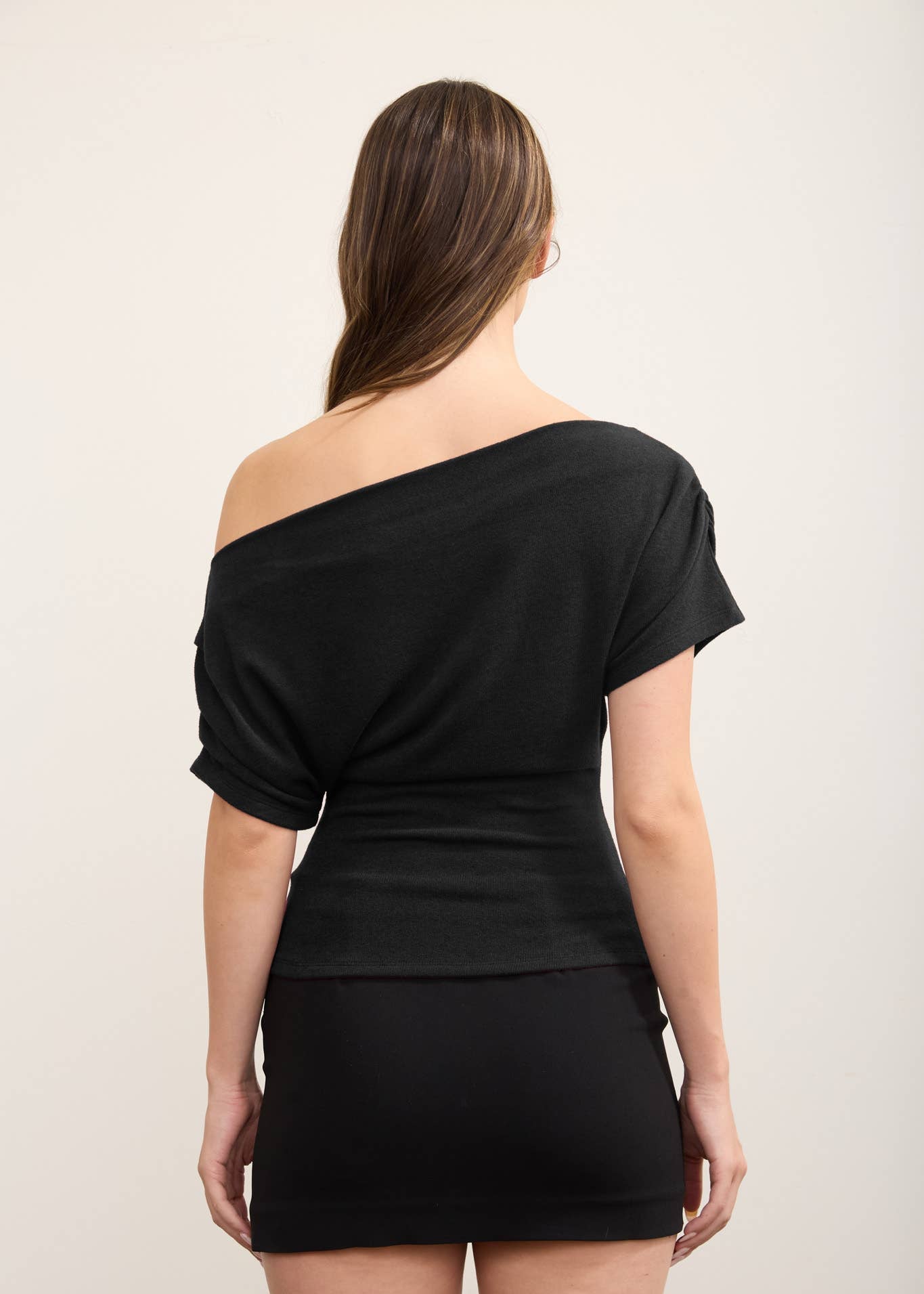 backside of women wearing black one shoulder knit top with mini skirt 