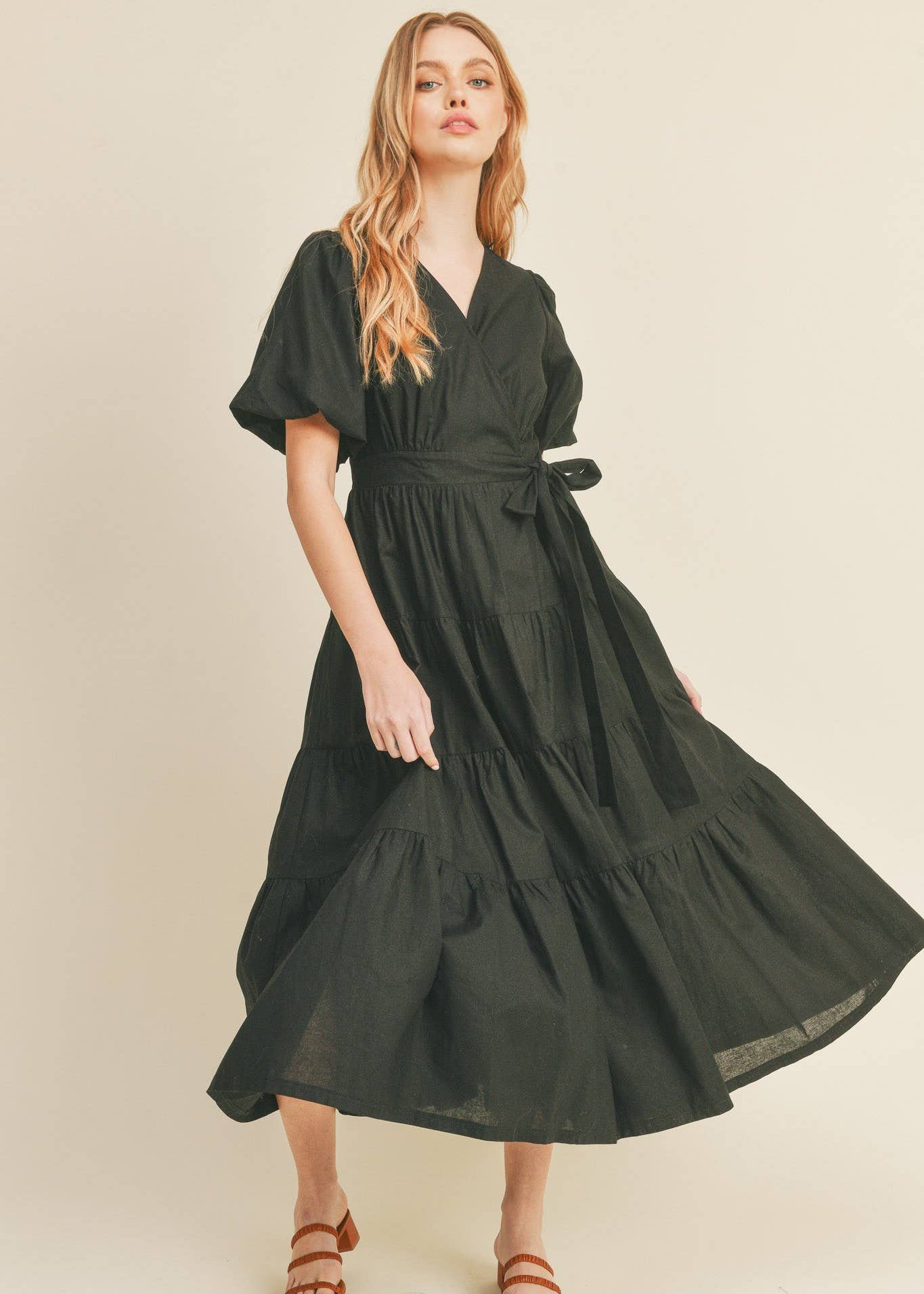 Woman wearing a black dress against a beige background