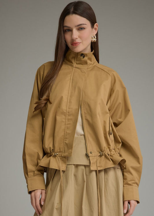 women wearing long sleeve tan jacket with drawstring waist and beige skirt and white undershirt