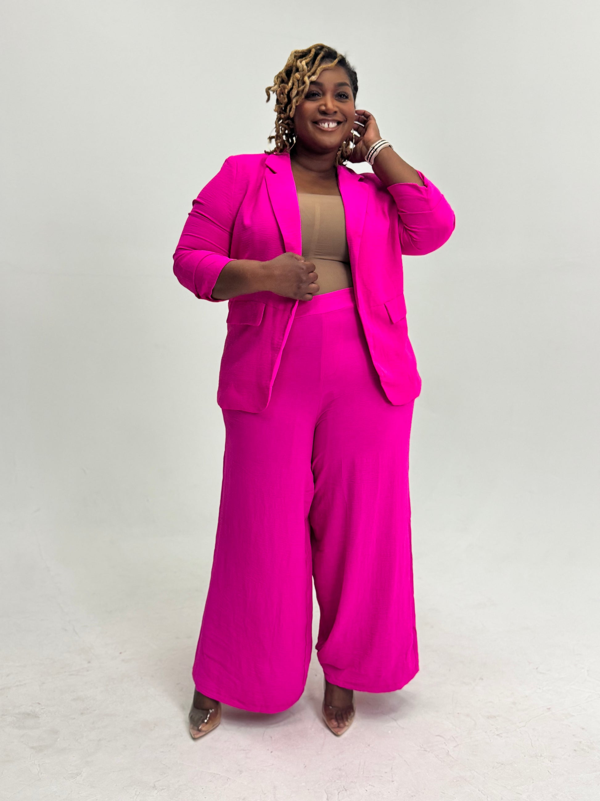 Plus size Woman wearing a bright pink pant suit against a white background