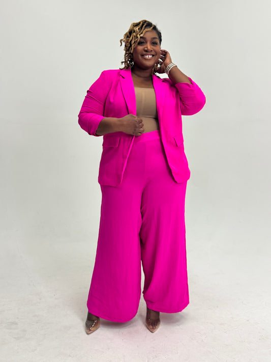 Plus size Woman wearing a bright pink pant suit against a white background
