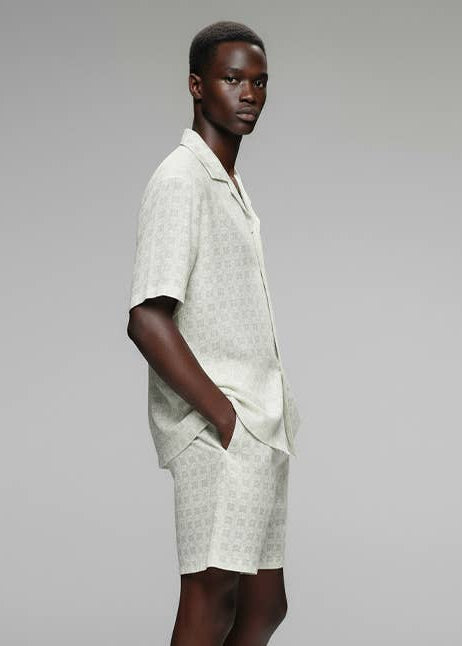 sideview of man wearing textured white collar shirt with matching shorts
