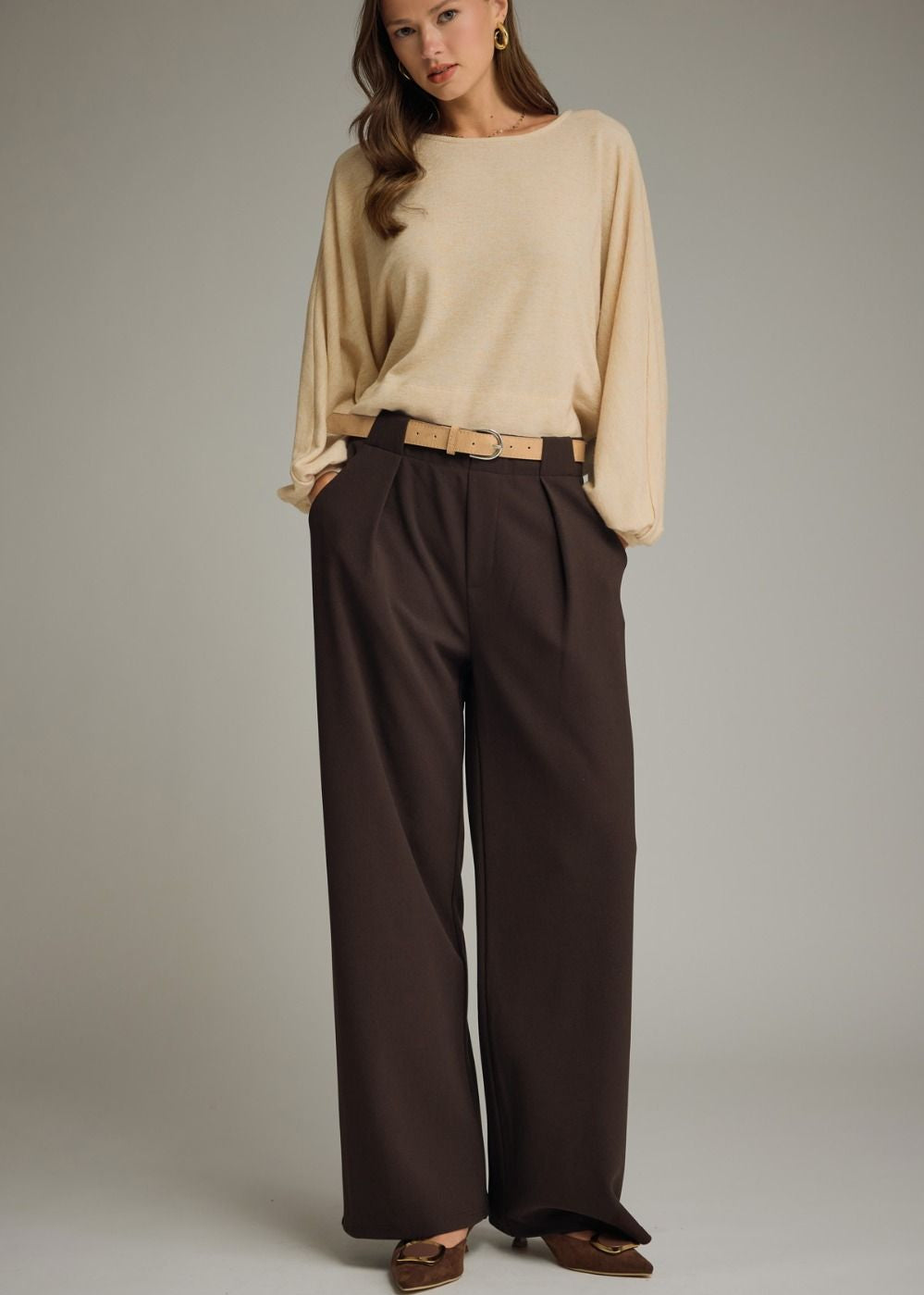 women wearing cream sweater and brown trousers with belt