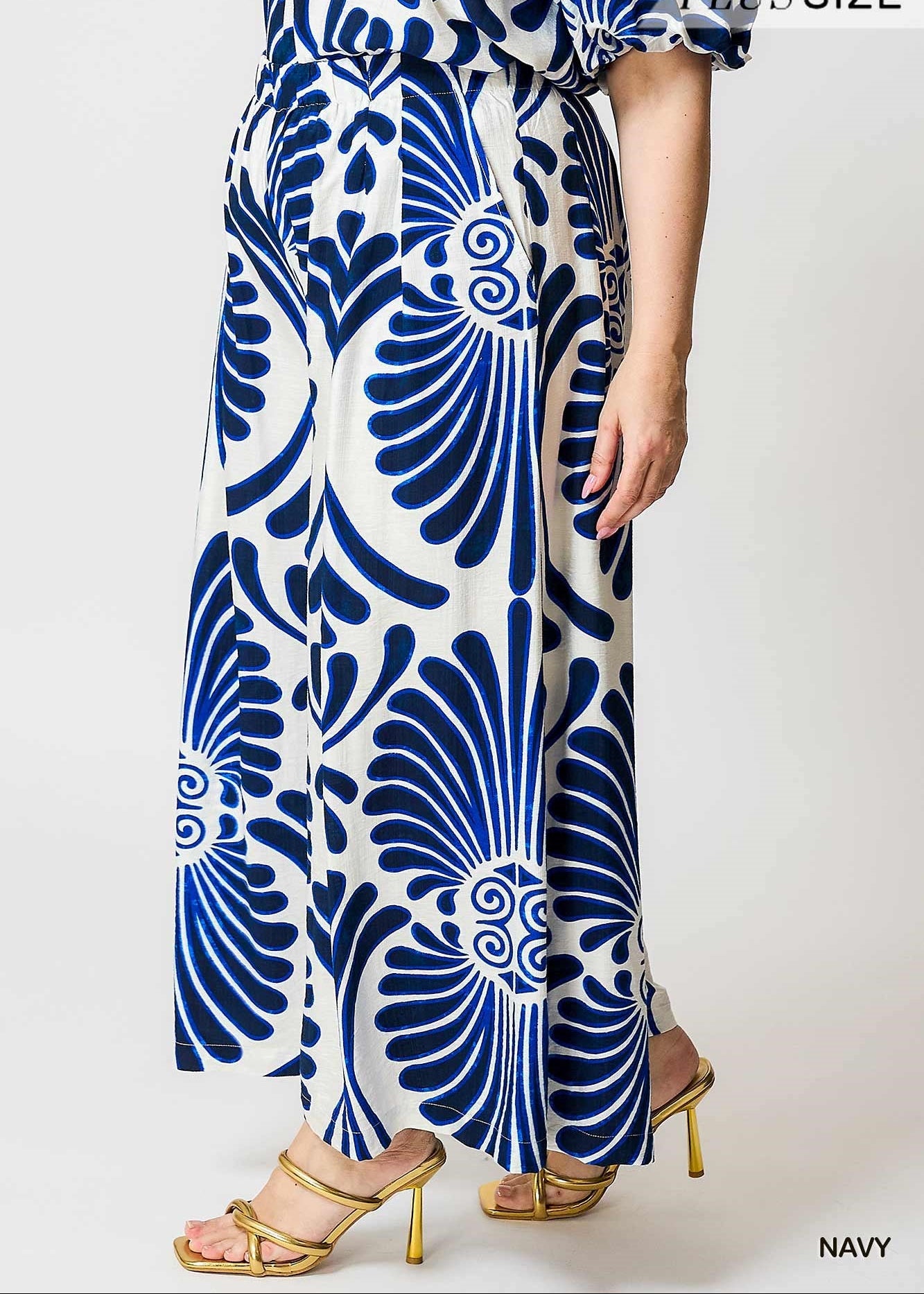 women wearing blue and white plus size print wide leg pants with strappy gold heal