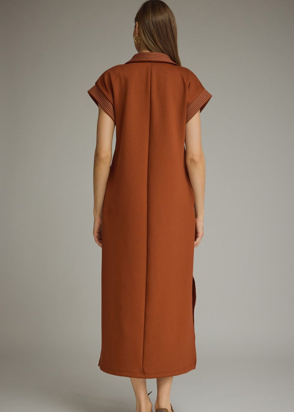 Woman wearing a long brown dress against a neutral background