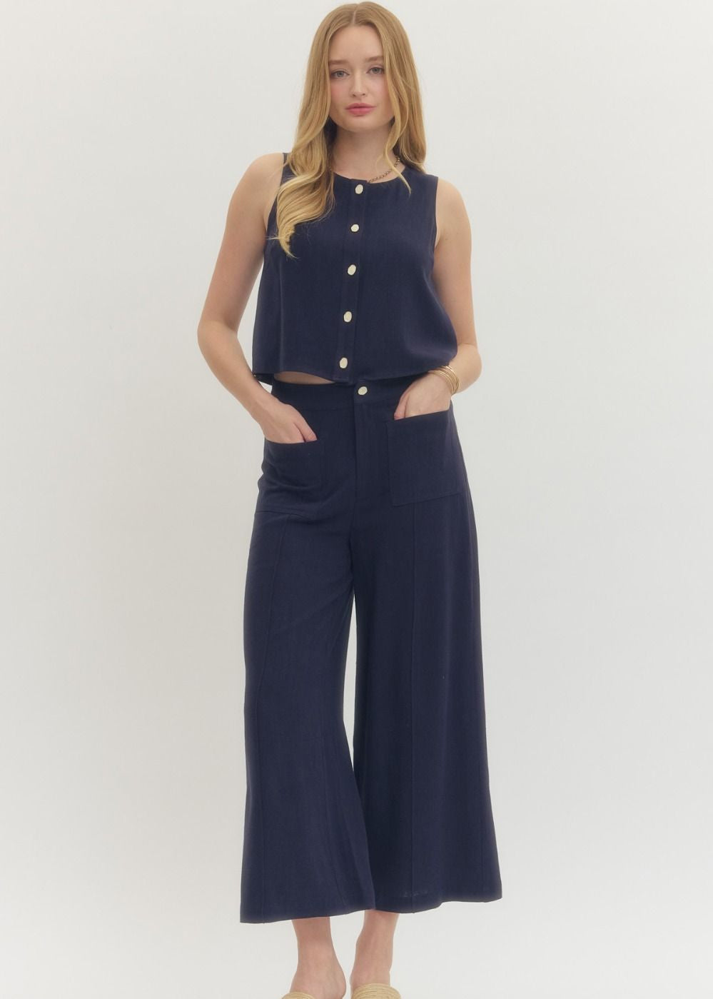 Woman wearing a navy sleeveless top and wide-leg pants on a white background