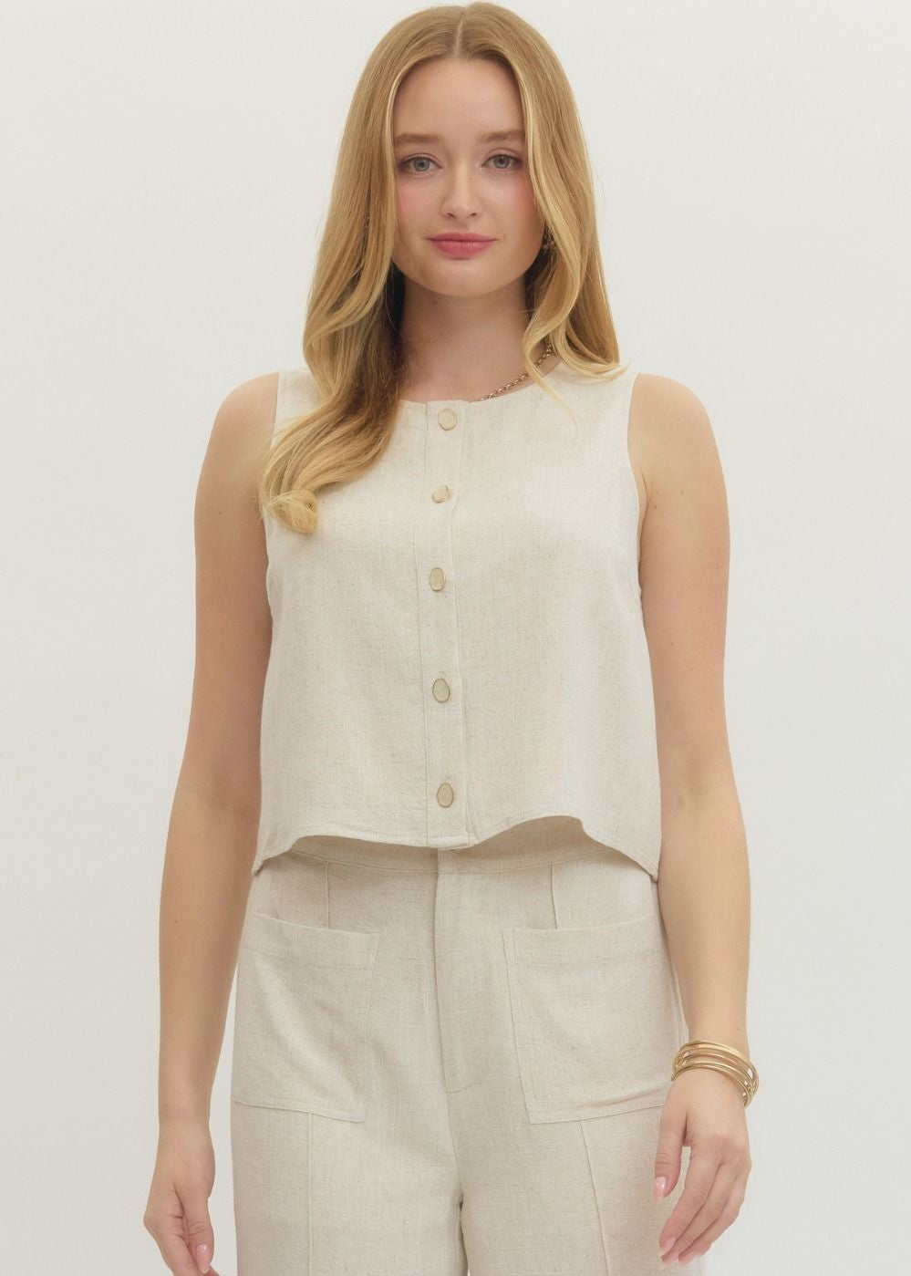 Woman wearing a sleeveless beige top and pants on a white background